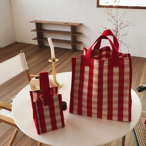 Detail of red and white checkered canvas tote bags in small and large sizes on a table
