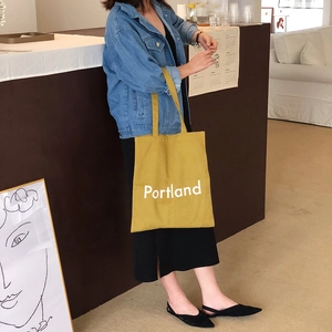 Tragefoto einer senfgelben Portland Canvas-Tasche kombiniert mit einer Denimjacke