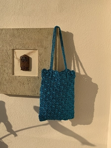 Detailed view of bright blue woven tote bag with intricate crochet texture and wavy edge