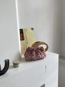 Pink lace pouch with 3D floral embroidery and pearl zipper detail on a mantle
