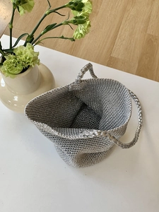 Gros plan du sac cabas tressé argenté montrant la texture et les détails de l'anse