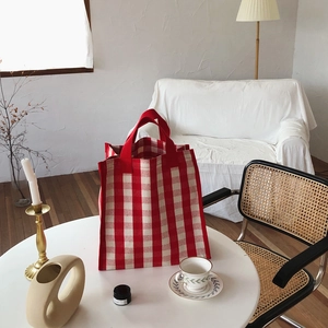 Detailed view of red and white checkered canvas tote bag on a white table