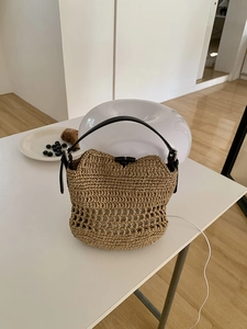 Detail of hand-woven straw beach bag with premium black leather handle and bamboo clasp