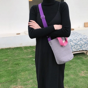 Détail du sac matelassé gris avec bandoulière violette et poignée rose sur modèle