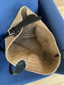 Handwoven straw tote bag with black leather shoulder strap and large internal capacity