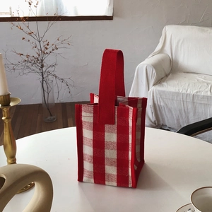 Close-up of red and white checkered canvas tote bag on a minimalist white table