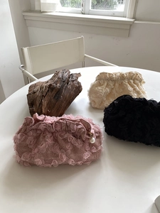 Detailed view of floral lace texture on evening clutches in pink, beige and black