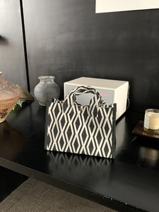 Détail du sac cabas en toile à damier noir et blanc avec poignées tissées et fermoir