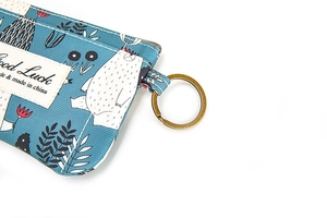 Détail du porte-monnaie en tissu bleu texturé avec imprimé ours et étiquette Good Luck