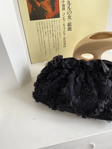 Detail of 3D black rose texture and pearl clasp on an elegant lace evening clutch bag