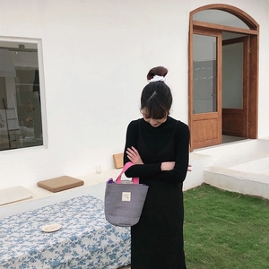 Détail d'un sac fourre-tout matelassé gris avec poignées rose vif et écusson logo carré