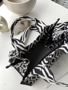 Détail du sac cabas en toile rayée noir et blanc avec bandoulière et boucles en métal