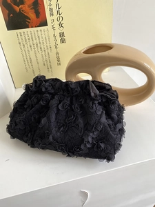 Detail of 3D rose textured fabric with pearl accent on a black evening clutch bag