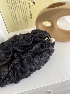 Detail of black lace cosmetic bag with 3D rose patterns and a large pearl zipper pull
