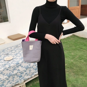 Photo extérieure d'une femme portant un sac en toile matelassé gris à anses roses