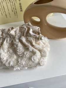 Detailed texture of white lace makeup bag with elegant 3D petals and pearl zipper pull