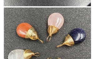 Detalle de colgantes de piedras preciosas en forma de gota envueltos en hilo dorado