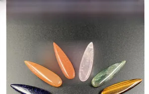 Variety of polished teardrop gemstones including quartz and agate for jewelry making