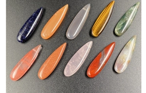 Macro display of diverse teardrop gemstones including rose quartz and tiger eye stones