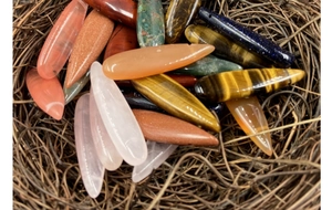 Flat teardrop semi-precious stone pendants on natural hay nest background