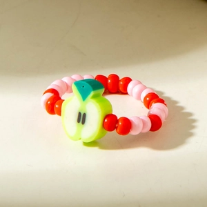 Detail of colorful fruit beaded ring with a cute green apple charm on elastic cord