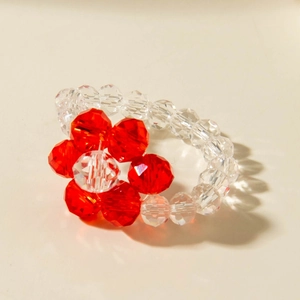 Macro shot of handmade beaded flower ring with red crystal beads and clear facets