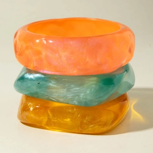 Three-piece set of wide resin bangles in orange, green, and amber with marble textures
