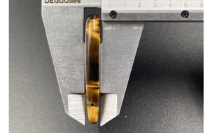 Tiger eye stone bead measurement showing 7-8mm thickness with a digital caliper