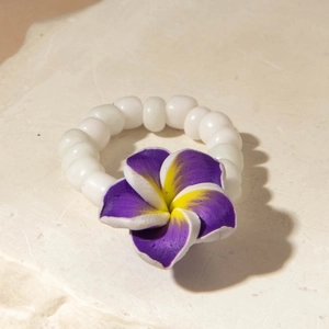 Macro shot of bohemian beaded ring featuring a purple plumeria flower on stone