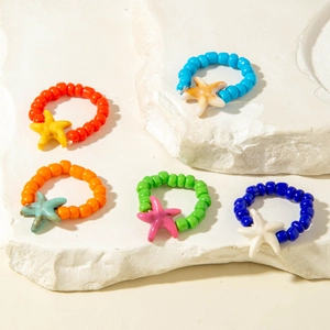 Close-up of five colorful starfish beaded rings on stone stands in a summer beach style