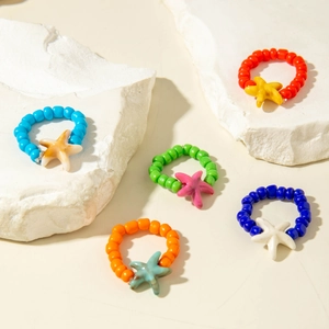 Detailed shot of five colorful beaded rings with marble texture starfish charms on stones