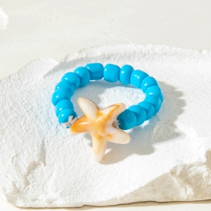 Detailed shot of handmade blue beaded ring featuring a beige resin starfish charm