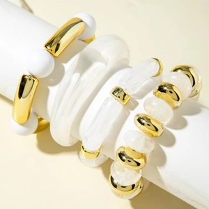 Detail of four-piece bracelet set featuring gold and white acrylic beads on a display