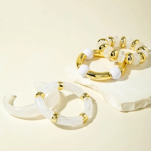 Detail of irregular acrylic beads and gold-toned metal tubes on minimalist bracelets