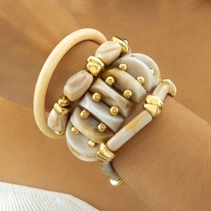 Detail of stacked marble resin bracelets with gold beads and a cream acrylic bangle
