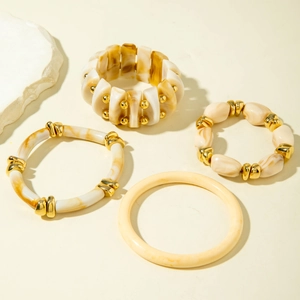 Detail of resin bangle set with marble pattern and gold metal beads in cream and amber