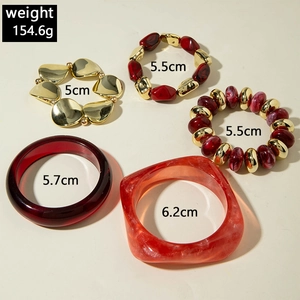 Detailed top view of red resin bangles and gold beaded stretch bracelets set