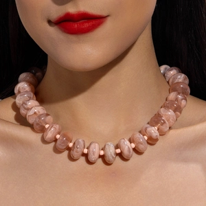 Detail of pink-orange acrylic beaded necklace with marble texture on model neck