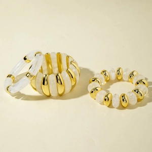 Detailed view of irregular acrylic bead bracelets with golden metal spacers in cream tone