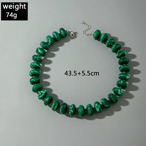 Macro shot of green acrylic beads with malachite texture and silver lobster clasp