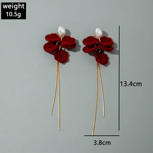 Detailed view of red velvet flower earrings with long gold tassels and white pearls