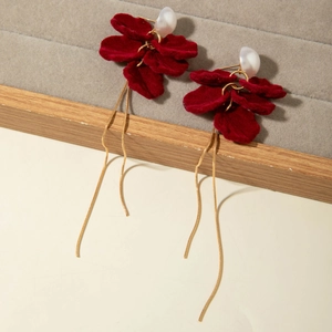 Detailed close-up of red velvet flower earrings with pearls and golden long chain tassels