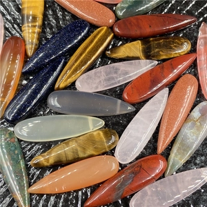 Various colorful gemstone teardrop pendants in rose quartz and tiger eye on black background