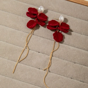 Detailed macro view of red velvet petal earrings with white pearls and gold chains