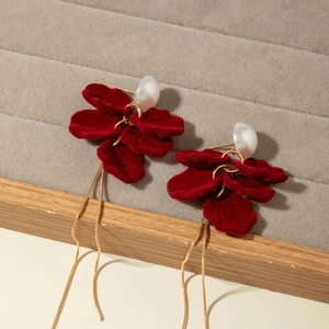 Detail of red velvet flower earrings with pearls and long gold tassel chains