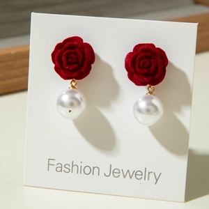 Detailed close-up of red velvet rose and pearl drop earrings on display card