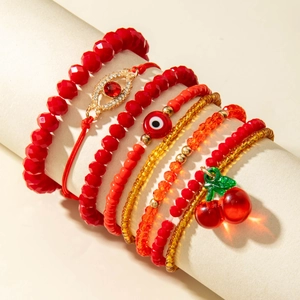 Layered beaded bracelet set with red cherry charms and evil eye beads on display