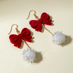 Detail of velvet red bow earrings with white pom-poms and gold-tone hooks