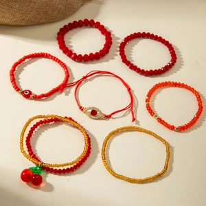 Detail view of 7-piece bohemian red beaded bracelet set with cherry and evil eye charms
