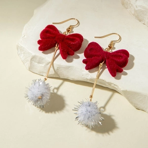 Detail of red velvet bow earrings with white fuzzy pompom and gold metallic rods